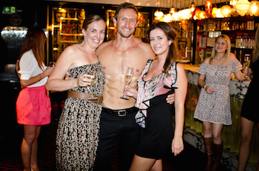 hens drinking champagne flanking their hot topless waiter