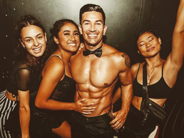 handsome and very well groomed topless waiter with group of partying hens